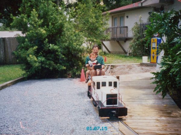 Child riding behind a white diesel locomotive on the gravel track
