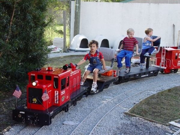 Kids riding a red miniature train on the mainline